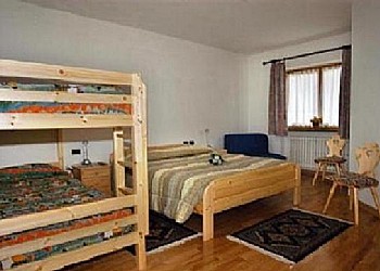 Appartamento a Predazzo. Camera padronale con letto matrimoniale, letto a castello in larice massiccio ( mt. 2,10 x 1,10 ) poltrona letto con doghe in legno e materasso in lattice.