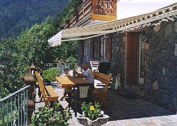 Appartamento a Predazzo. Tavolo esterno di un' appartamento con tenda per il sole.