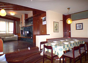 Appartamento a Predazzo. <p> Sala da pranzo, con grande tavolo allungabile e TV <p>The spacious and elegant living room with fireplace and dining room